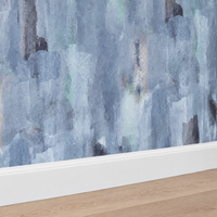 Gros plan sur une plinthe blanche sous un papier peint aquarelle abstrait bleu et gris