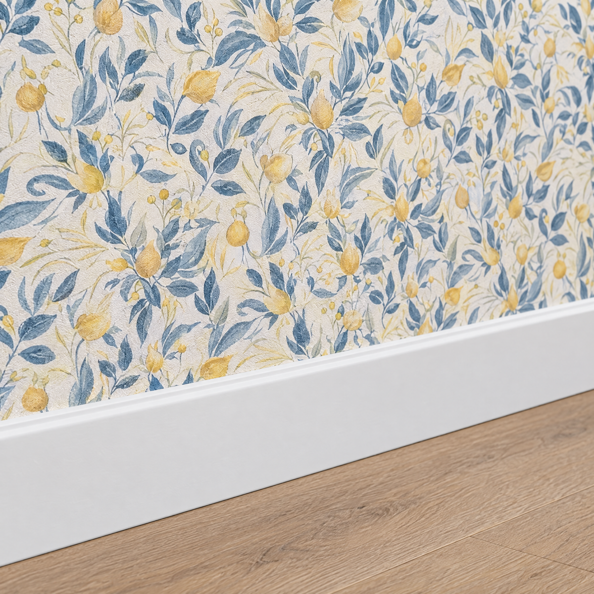 Gros plan sur une plinthe blanche sous un papier peint floral bleu et blanc