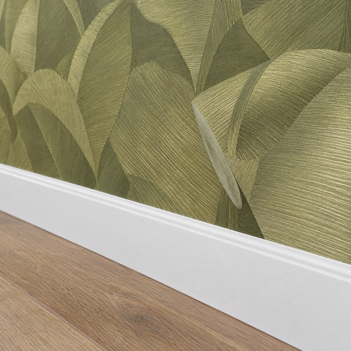 Gros plan sur une plinthe blanche sous un papier peint feuilles tropicales vert olive