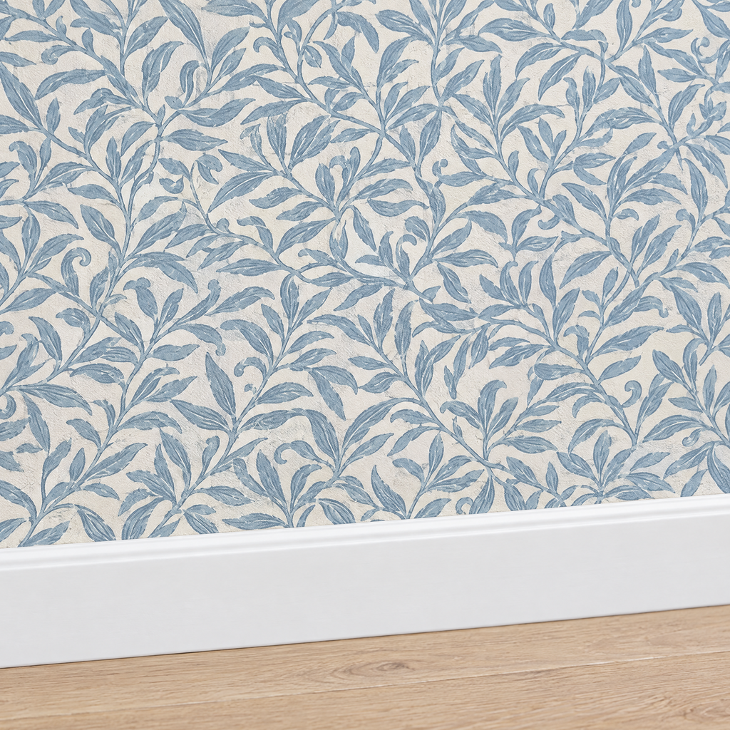 Gros plan plinthe blanche sous papier peint feuillage bleu poudré