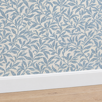Gros plan plinthe blanche sous papier peint feuillage bleu poudré