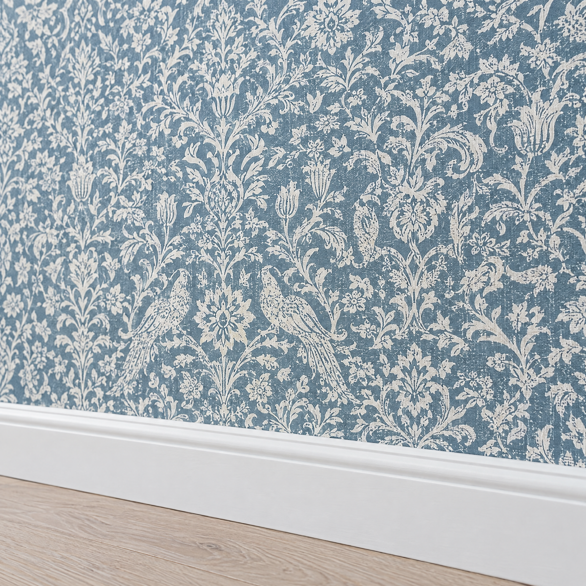 Papier peint damassé bleu gris et crème au-dessus d'une plinthe blanche