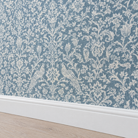 Papier peint damassé bleu gris et crème au-dessus d'une plinthe blanche