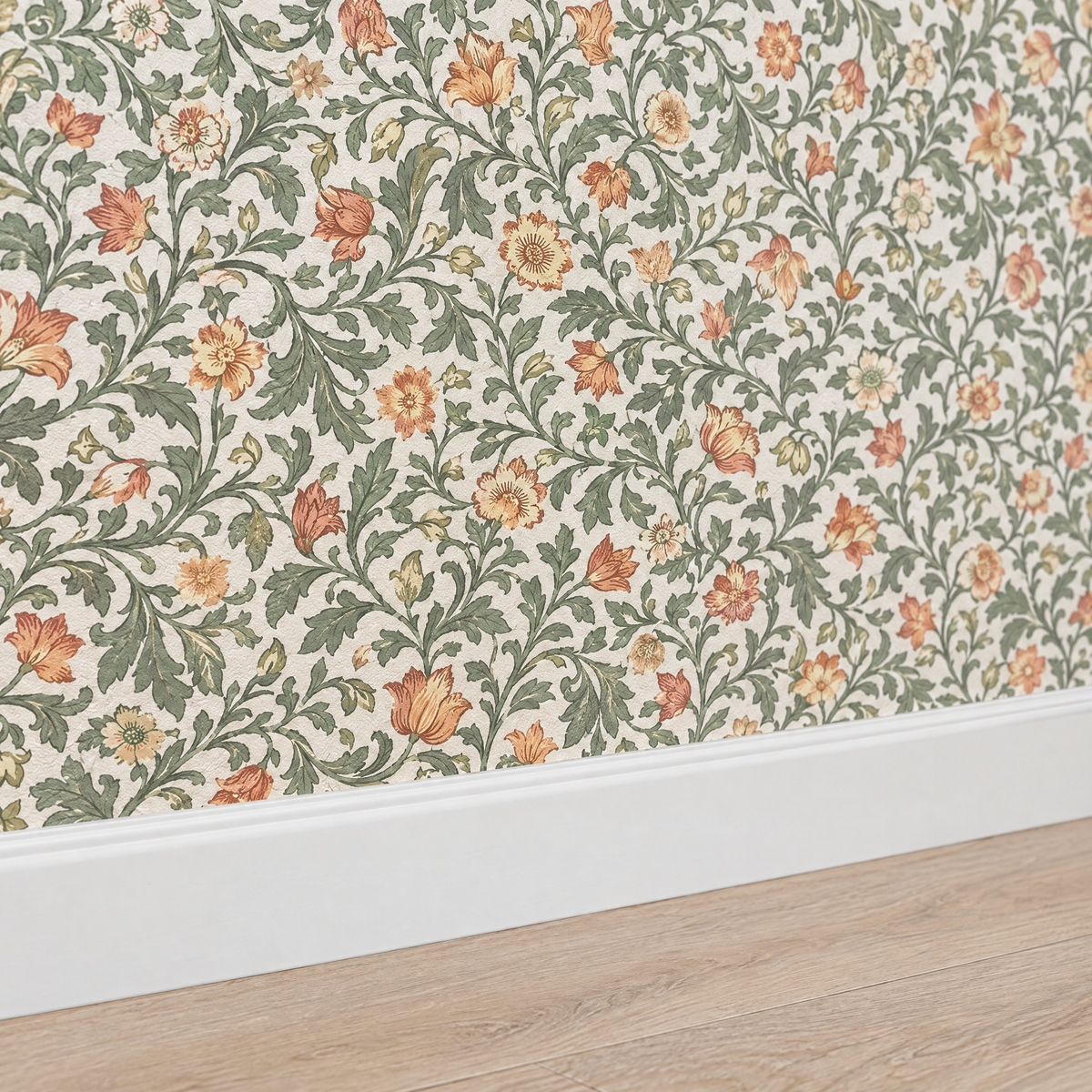 Papier peint floral vert sauge et pêche au-dessus d'une plinthe blanche