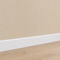 Gros plan sur le papier peint uni aspect lin beige au-dessus d'une plinthe blanche