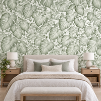 Papier peint feuilles de monstera vert et blanc derrière une tête de lit en chambre