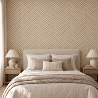 Papier peint chevrons effet parquet beige et crème derrière une tête de lit en chambre